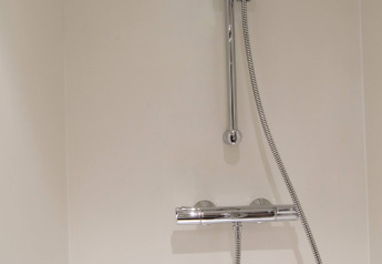 Shower with adjustable showerhead and chrome fittings at RoyalLodge safari tent in Slow Village Provence Occitane.