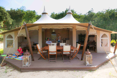 Tienda safari RoyalLodge en Slow Village Provence Occitane, Francia, con terraza de madera y familia relajándose.