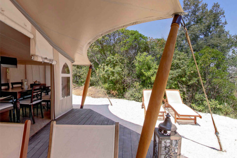 Buitenzicht vanuit een safaritent bij RoyalLodge in Slow Village Provence Occitane met ligstoelen en groen.