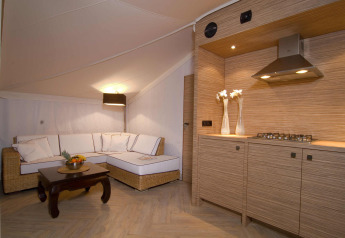Interior of RoyalLodge safari tent featuring a kitchenette and sofa at Slow Village Provence Occitane, France.