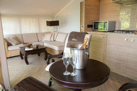 Interior de una lujosa tienda safari RoyalLodge con cocina moderna, sofá y champán en Slow Village Provence Occitane.