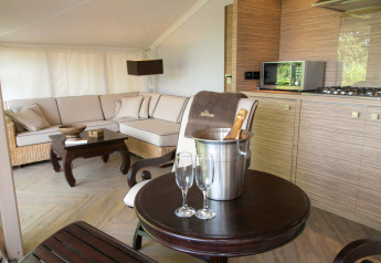 Interior of a luxury safari tent RoyalLodge with modern kitchen, sofa, table and champagne at Slow Village Provence Occitane.