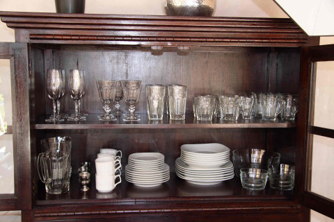 Een houten kast met glaswerk, kopjes, borden en kommen in RoyalLodge, Slow Village Provence Occitane.