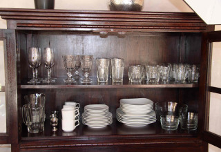 Een houten kast met glaswerk, kopjes, borden en kommen in RoyalLodge, Slow Village Provence Occitane.