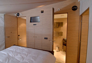 Luxueus safaritent-interieur met houten panelen, bed en badkamer bij RoyalLodge, Slow Village Provence Occitane.