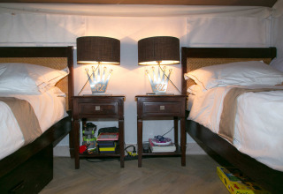 Interior de la tienda safari RoyalLodge con dos camas, mesitas de noche y lámparas en Slow Village Provence Occitane.