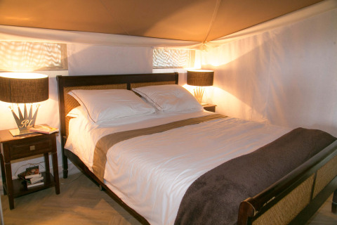 Slaapkamer in de RoyalLodge safaritent bij Slow Village Provence Occitane in Frankrijk, met bed en lampen.