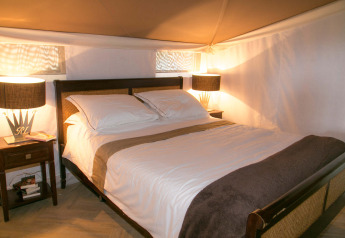 Camera da letto nella tenda safari RoyalLodge a Slow Village Provence Occitane, Francia, con letto grande e lampade.