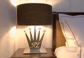 Stylish bedside lamp with crown-shaped base and black shade on nightstand in RoyalLodge safari tent, Provence.