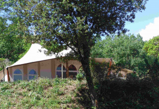 Tienda safari RoyalLodge en Slow Village Provence Occitane, Francia, rodeada de árboles verdes y vegetación.