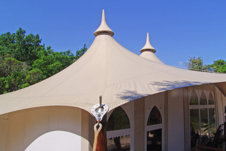 Tienda safari con torretas puntiagudas y lona beige en Slow Village Provence Occitane, Francia, bajo un cielo azul.