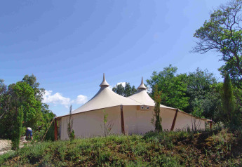Het RoyalLodge safaritent bij Slow Village Provence Occitane in Frankrijk, omgeven door bomen en natuur.