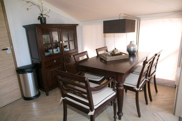 Comedor elegante en la tienda safari RoyalLodge en Slow Village Provence Occitane, Francia, con muebles de madera.
