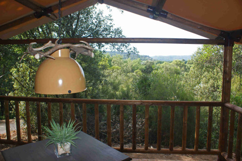 Zicht vanuit een SunLodge Safari tent bij Slow Village Provence Occitane in Frankrijk, met lamp en bomen.