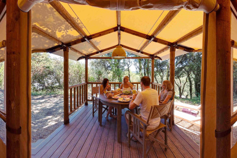 Gezin aan tafel op het houten terras van een SunLodge Safari tent bij Slow Village Provence Occitane.
