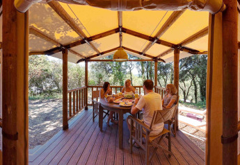Gezin geniet van een maaltijd op het overdekte terras van een SunLodge Safari tent bij Slow Village Provence Occitane.