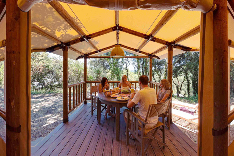 Familia compartiendo una comida en la terraza cubierta de una tienda SunLodge Safari en Slow Village Provence Occitane.
