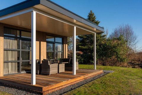 Lodge moderno con terraza cubierta y muebles de exterior en Holiday Resort 't Schuttenbelt, Países Bajos.