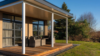 Lodge moderno con terraza cubierta y muebles de exterior en Holiday Resort 't Schuttenbelt, Países Bajos.