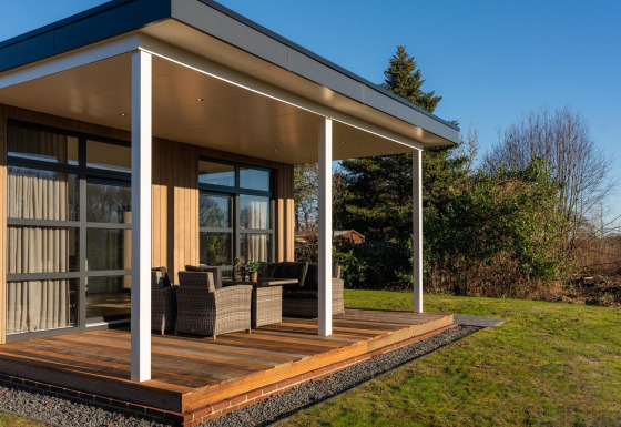 Lodge moderno con terraza cubierta y muebles de exterior en Holiday Resort 't Schuttenbelt, Países Bajos.