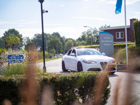 Coche blanco sale de Recreatiepark het Esmeer con cartel de despedida en varios idiomas, Gelderland, Países Bajos.