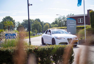 Witte wagen rijdt Recreatiepark het Esmeer uit, met afscheidsbord in verschillende talen, Gelderland, Nederland.