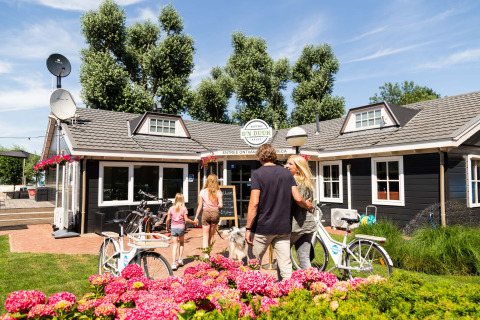 Famille arrivant en vélo au Recreatiepark het Esmeer, parc de vacances en Gueldre, Pays-Bas, été.