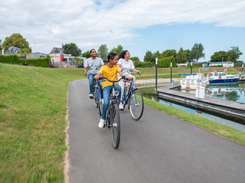 Un gruppo di persone va in bicicletta su un sentiero vicino all’acqua al Recreatiepark het Esmeer, in Gelderland, Paesi Bassi.