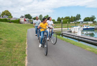 Un groupe de personnes fait du vélo sur un chemin près de l’eau au Recreatiepark het Esmeer en Gueldre, Pays-Bas.