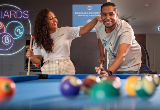 Zwei fröhliche Menschen spielen Billard im Freizeitpark het Esmeer in Gelderland, Niederlande.