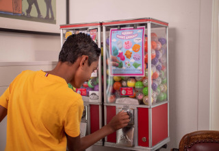 Boy in yellow shirt uses a toy capsule machine with squishy animals at Recreatiepark het Esmeer, Gelderland.