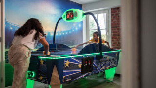 Dos personas juegan air hockey en una sala de juegos luminosa del Recreatiepark het Esmeer en Gelderland.