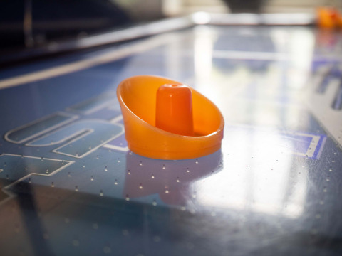 Ein orangefarbener Airhockey-Schieber auf einem Airhockey-Tisch im Recreatiepark het Esmeer, Gelderland, Niederlande.