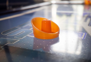 Een oranje airhockey-sticker op een airhockeytafel in Recreatiepark het Esmeer, Gelderland, Nederland.