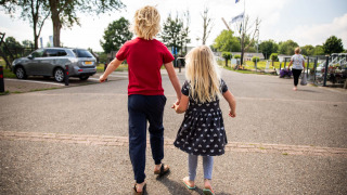 Dos niños se dan la mano y caminan juntos en un parque de vacaciones en Gelderland, Países Bajos.