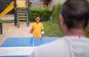 Ragazzo gioca a ping pong all’aperto a Recreatiepark het Esmeer, Gelderland, Olanda, vicino a un parco giochi.