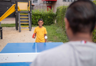 Junge spielt Tischtennis im Freien im Recreatiepark het Esmeer, Gelderland, Niederlande, auf einem Spielplatz.