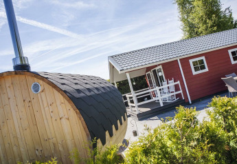 Lounge Veluwe con sauna al parco vacanze De Boshoek nei Paesi Bassi, con baita rossa e sauna in legno.