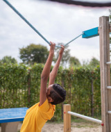 Kind spielt am Seil auf dem Spielplatz im Recreatiepark het Esmeer, einem Ferienpark in Gelderland.