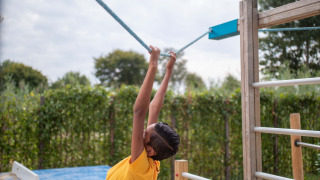 Niño jugando y colgándose de una cuerda en el parque infantil de Recreatiepark het Esmeer en Gelderland.