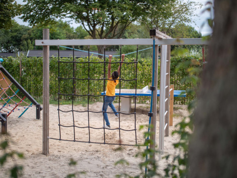 Un niño juega en una red para trepar en Recreatiepark het Esmeer en Gelderland, Países Bajos.