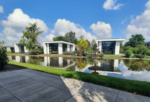 Cabañas modernas junto a un estanque con fuente en Résidence Lichtenvoorde, parque vacacional en Gelderland, Países Bajos.