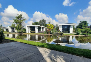 Modern holiday lodges by a pond with a fountain at Résidence Lichtenvoorde holiday park in Gelderland, Netherlands.