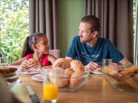 Vader en dochter ontbijten met een glimlach bij Résidence Lichtenvoorde vakantiepark in Gelderland, Nederland.