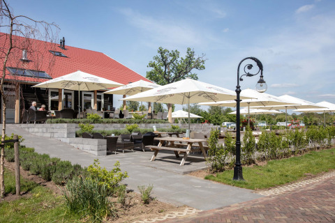 Terraza exterior con sombrillas y asientos en Résidence Lichtenvoorde, parque vacacional en Gelderland, Países Bajos.