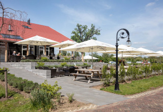 Terrazza all'aperto con ombrelloni e posti a sedere a Résidence Lichtenvoorde, parco vacanze in Gelderland, Paesi Bassi.