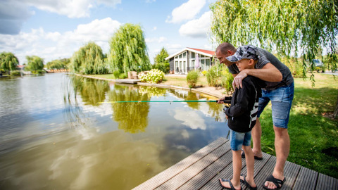 Padre e figlio pescano insieme sul lago a Résidence Lichtenvoorde, parco vacanze in Gheldria, Paesi Bassi.