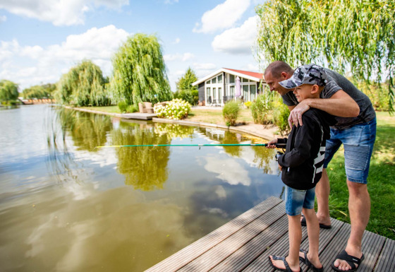 Padre e figlio pescano insieme sul lago a Résidence Lichtenvoorde, parco vacanze in Gheldria, Paesi Bassi.