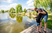 Far og søn fisker sammen ved en sø i Résidence Lichtenvoorde, et feriepark i Gelderland, Holland.