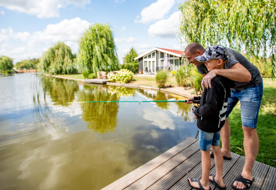 Vader en zoon vissen samen aan het meer bij Résidence Lichtenvoorde, een vakantiepark in Gelderland, Nederland.